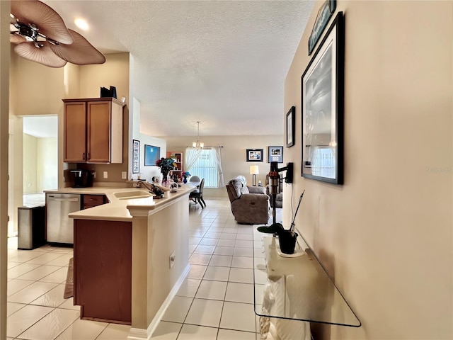 kitchen featuring a sink, a peninsula, stainless steel dishwasher, and light tile patterned floors