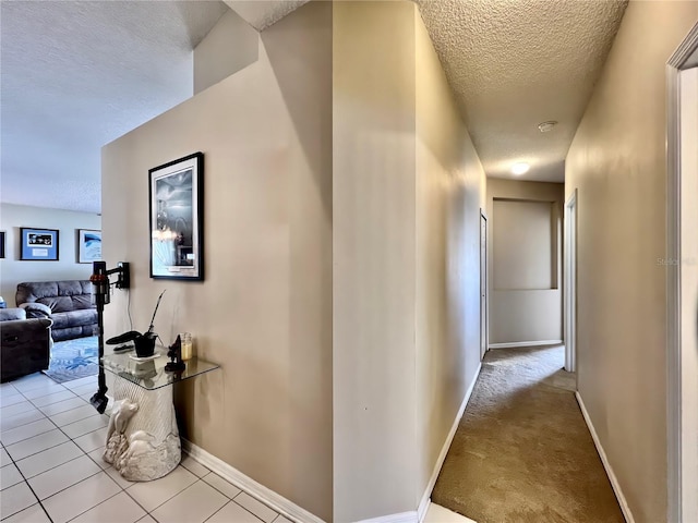 corridor with baseboards, carpet flooring, a textured ceiling, and tile patterned floors