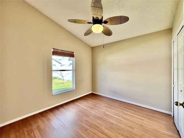 unfurnished room featuring a ceiling fan, baseboards, vaulted ceiling, and light wood finished floors