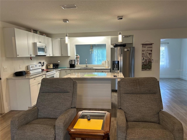 kitchen with open floor plan, white appliances, a sink, and white cabinets