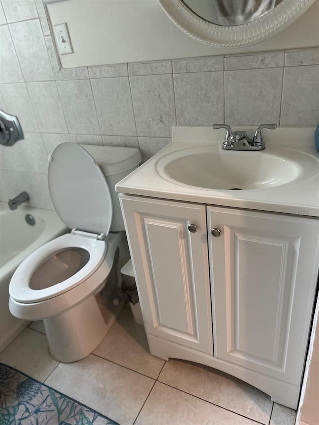 bathroom with tasteful backsplash, toilet, tile patterned floors, vanity, and tile walls