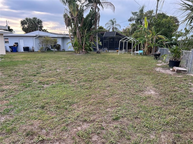 view of yard featuring a lanai, fence, and central AC unit