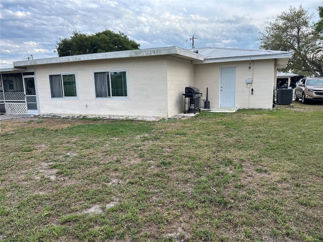 back of house with cooling unit, metal roof, and a yard