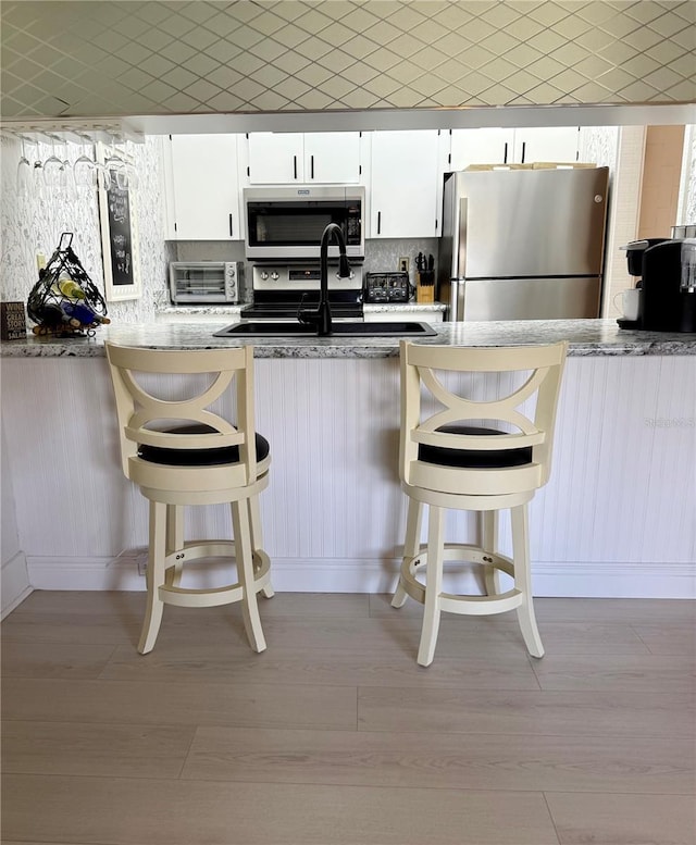 kitchen with tasteful backsplash, a breakfast bar area, stainless steel appliances, and light wood-style floors