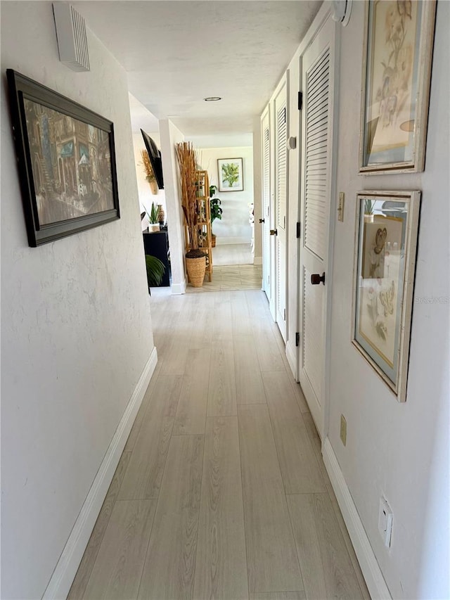 hallway featuring wood finished floors and baseboards