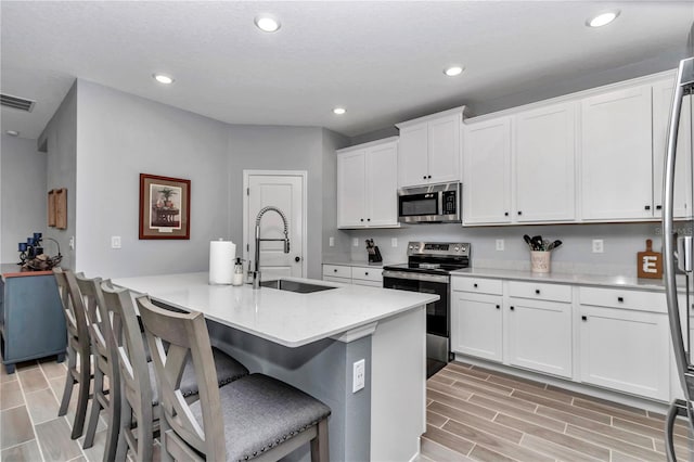 kitchen featuring light countertops, visible vents, appliances with stainless steel finishes, white cabinets, and a sink