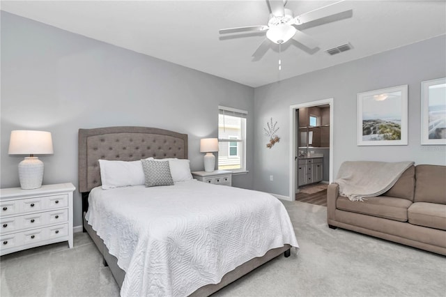 bedroom with light carpet, baseboards, visible vents, and ensuite bathroom