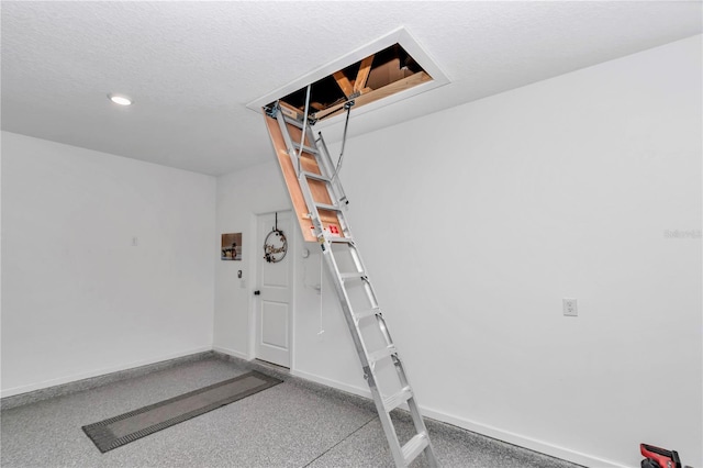 exercise area with a textured ceiling, a garage, and baseboards