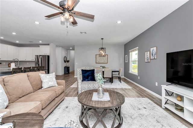 living room with light wood-type flooring, baseboards, visible vents, and recessed lighting