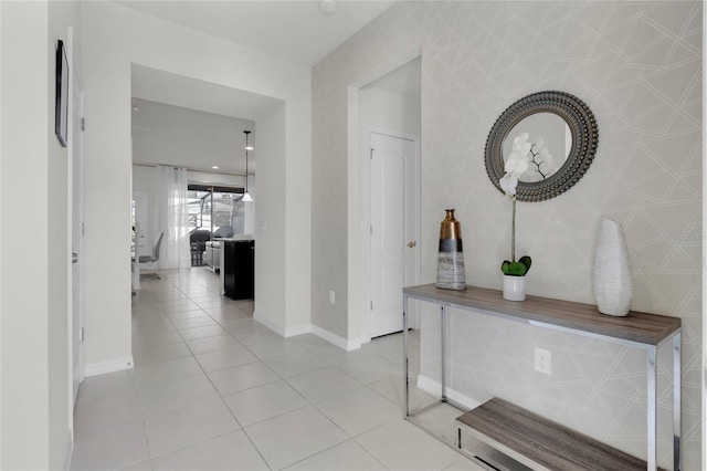 corridor with light tile patterned floors, baseboards, and wallpapered walls