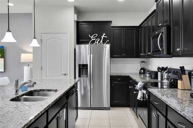 kitchen with light tile patterned floors, dark cabinetry, stainless steel appliances, and a sink