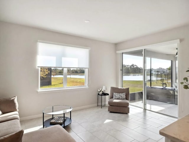 living area with a water view, light tile patterned flooring, and baseboards