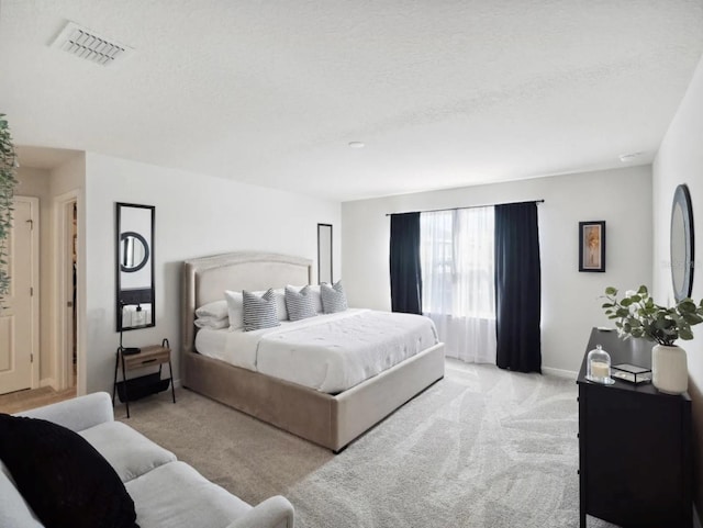 bedroom with light carpet, baseboards, visible vents, and a textured ceiling