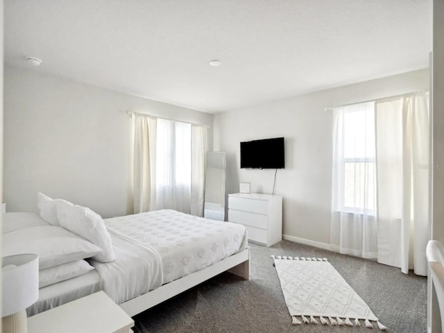 carpeted bedroom featuring multiple windows and baseboards