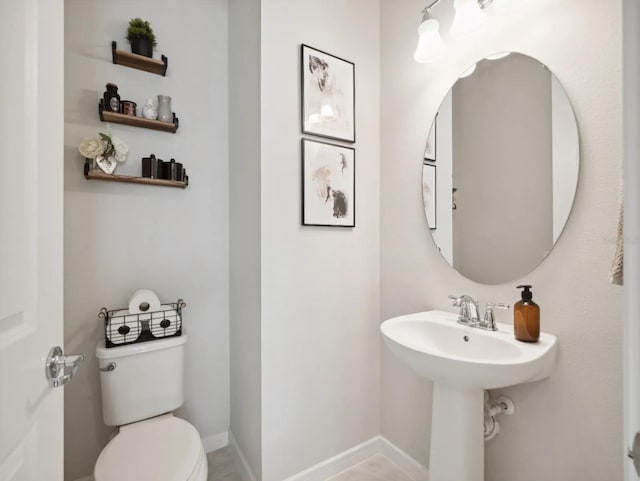 half bath featuring toilet and baseboards