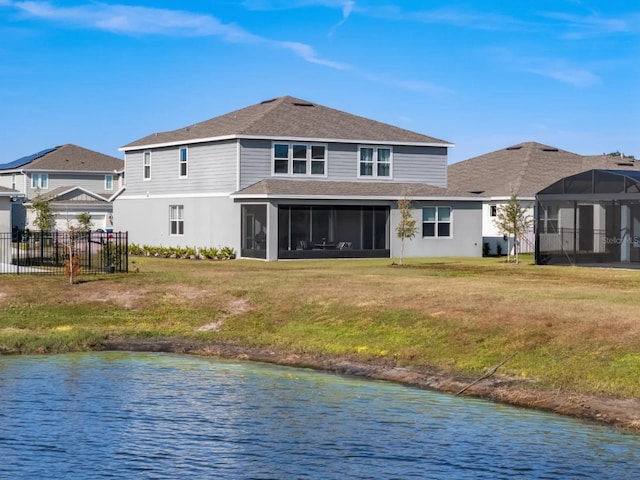 back of property with a sunroom, a water view, a yard, and fence