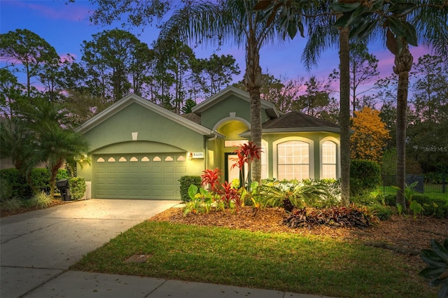 view of front of house with a garage, driveway, and stucco siding