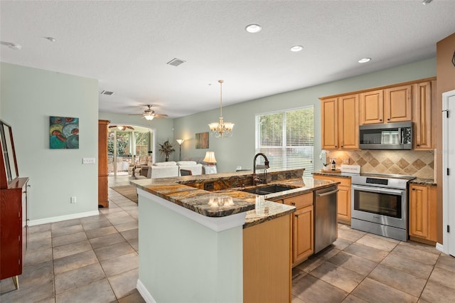 kitchen featuring visible vents, a sink, a kitchen island with sink, stainless steel appliances, and backsplash