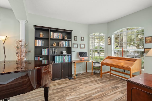 sitting room featuring baseboards, wood finished floors, and ornate columns