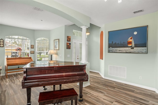 living area featuring arched walkways, wood finished floors, and visible vents