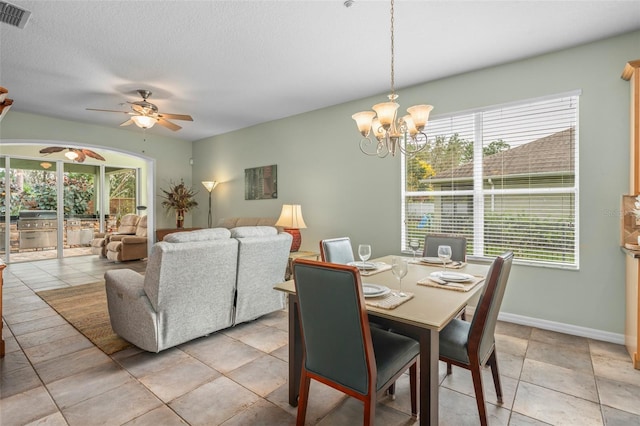 dining space with visible vents, plenty of natural light, a textured ceiling, and ceiling fan with notable chandelier