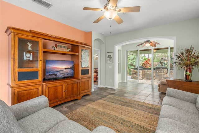 living room with arched walkways, visible vents, ceiling fan, and baseboards