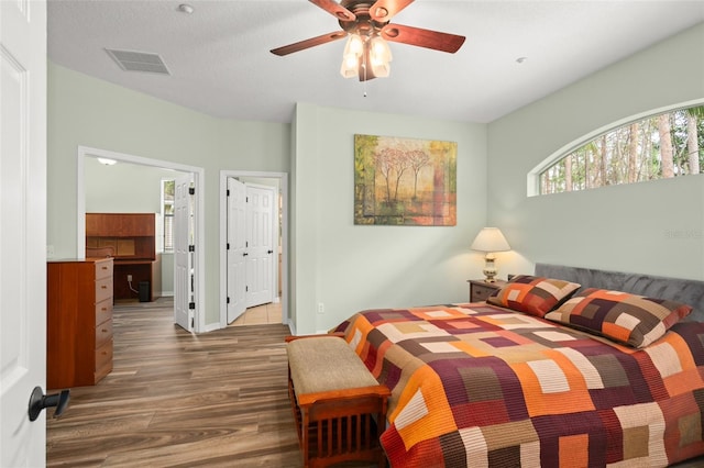 bedroom with visible vents, connected bathroom, ceiling fan, wood finished floors, and baseboards