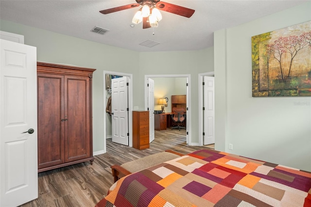 bedroom with a closet, visible vents, a spacious closet, dark wood-type flooring, and a ceiling fan