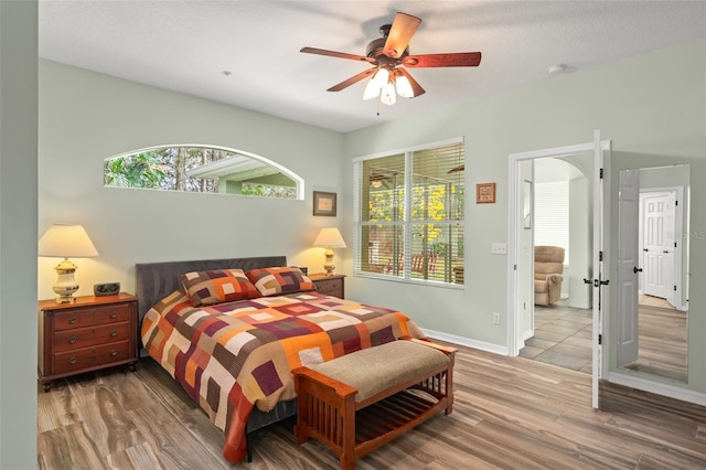 bedroom featuring ceiling fan, baseboards, and wood finished floors