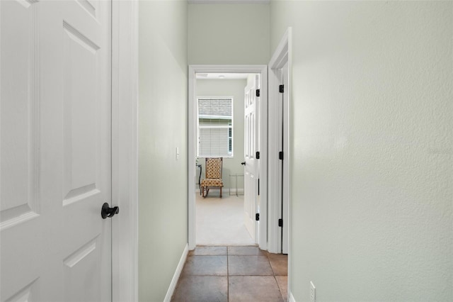 hall featuring baseboards and light tile patterned floors