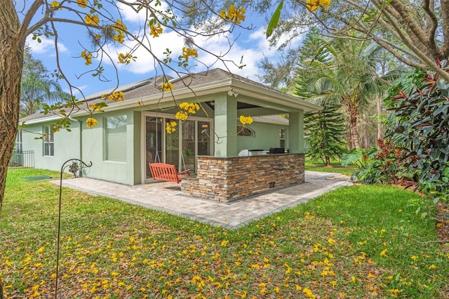 rear view of house featuring a patio area, a yard, exterior kitchen, and stucco siding