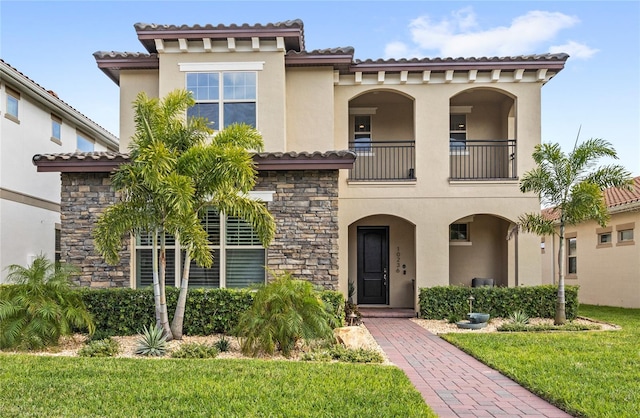 mediterranean / spanish house with a balcony, stone siding, and stucco siding