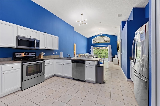 kitchen with light tile patterned floors, an inviting chandelier, appliances with stainless steel finishes, open floor plan, and a peninsula