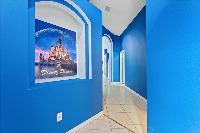 hallway with tile patterned flooring, visible vents, and baseboards