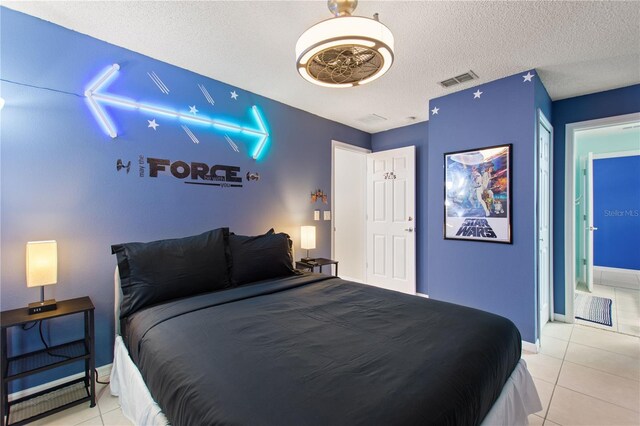 bedroom featuring light tile patterned floors, baseboards, visible vents, and a textured ceiling