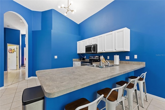 kitchen with arched walkways, stainless steel appliances, light tile patterned floors, and a breakfast bar