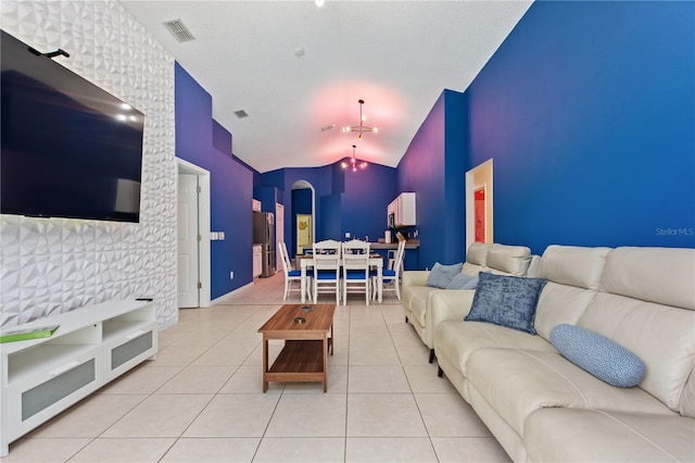 living room with tile patterned flooring, visible vents, and vaulted ceiling