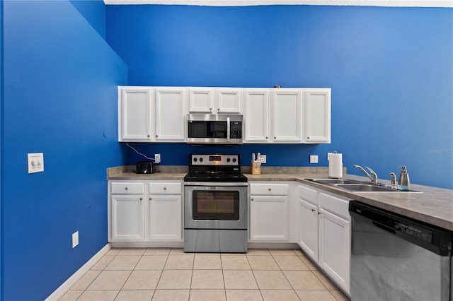 kitchen with light tile patterned floors, stainless steel appliances, a sink, and white cabinets