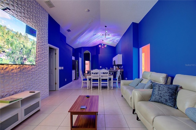 tiled living room with lofted ceiling, an accent wall, and visible vents