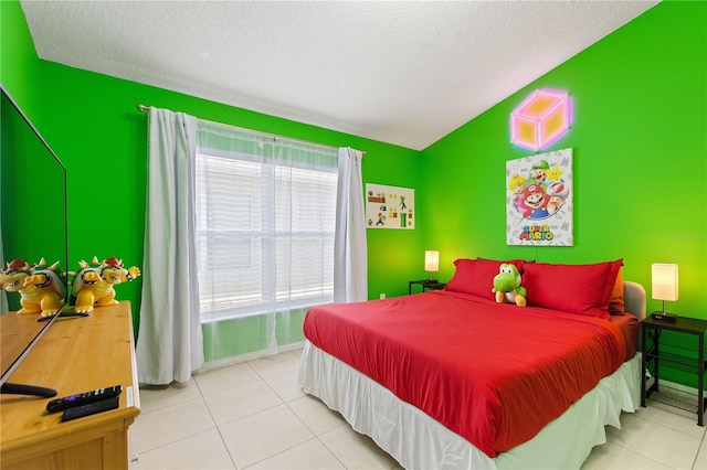 bedroom with an accent wall, lofted ceiling, a textured ceiling, and tile patterned floors