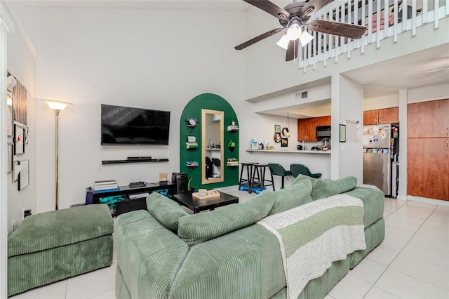 living room featuring visible vents, ceiling fan, a high ceiling, and tile patterned floors