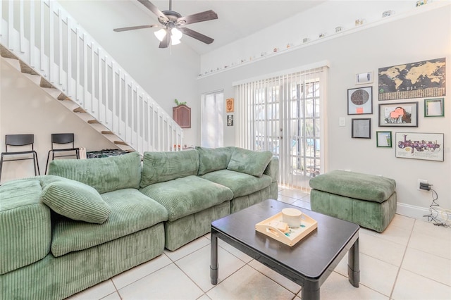 tiled living room featuring lofted ceiling, ceiling fan, stairway, and baseboards