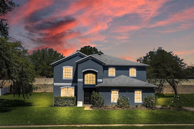 view of front of home featuring a shingled roof, a front yard, fence, and stucco siding