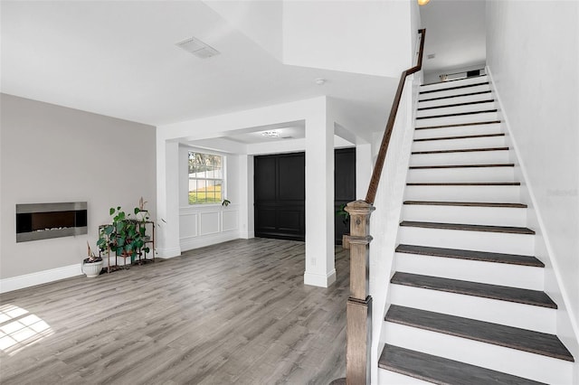 foyer entrance with stairway, wood finished floors, visible vents, and baseboards