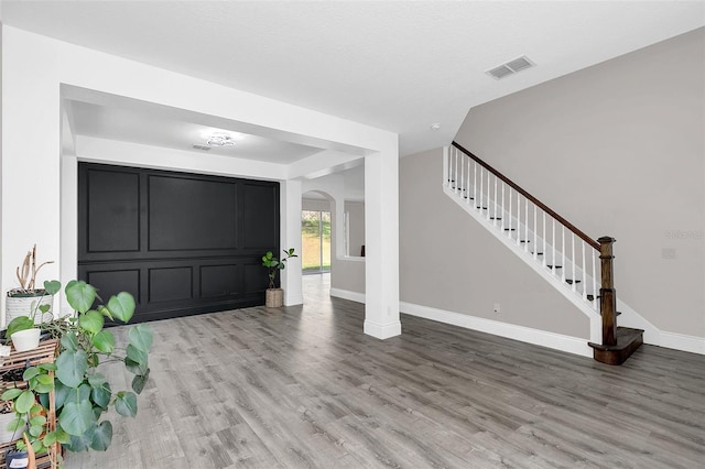 foyer entrance featuring baseboards, visible vents, arched walkways, stairs, and light wood-type flooring