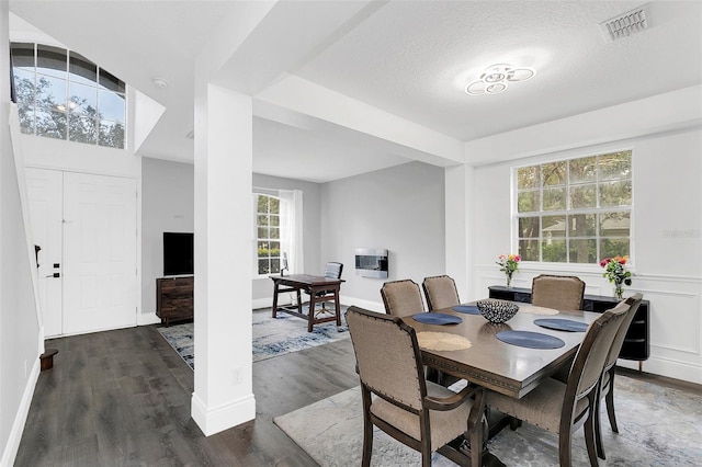 dining room featuring a wainscoted wall, dark wood finished floors, heating unit, visible vents, and a textured ceiling