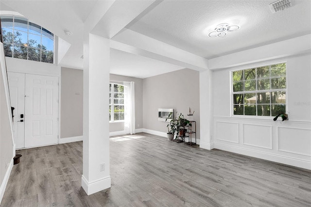 entryway with visible vents, a decorative wall, a textured ceiling, wood finished floors, and baseboards