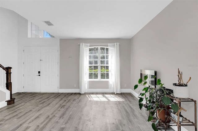 foyer entrance featuring stairway, baseboards, visible vents, and wood finished floors