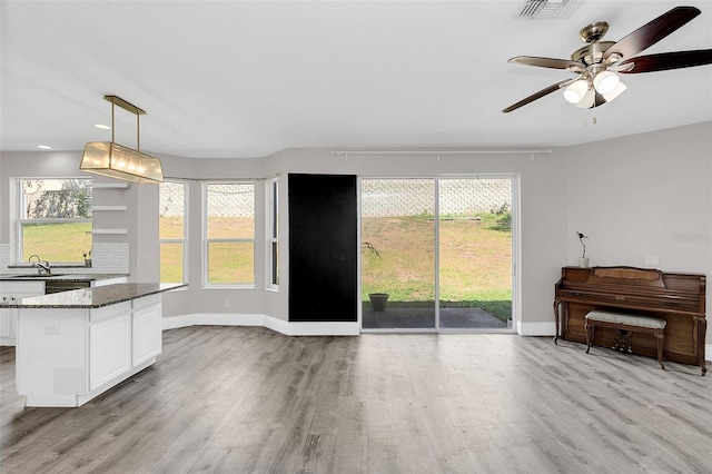 interior space featuring baseboards, visible vents, ceiling fan, and light wood finished floors