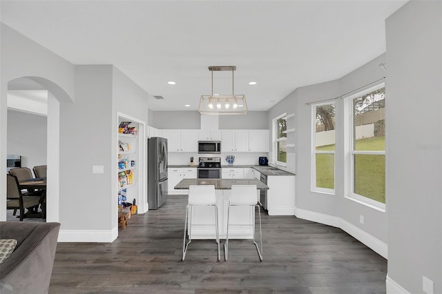 kitchen with a sink, white cabinets, appliances with stainless steel finishes, backsplash, and a center island